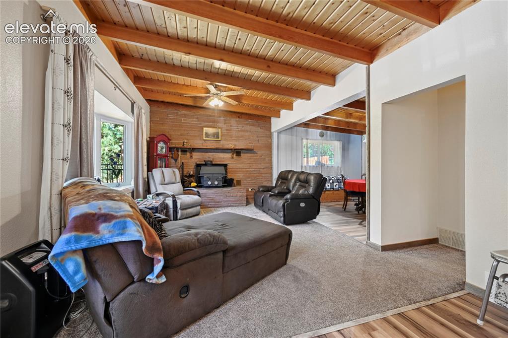 Image 9 of 50: Wood-paneled vaulted ceiling with exposed beams, brick-clad fireplace, and 