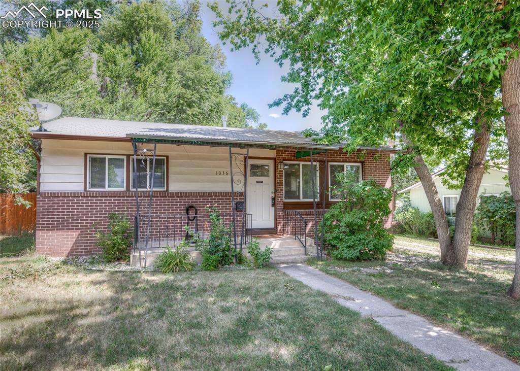 Caption: View of front of property with brick siding, a front lawn, and a porch