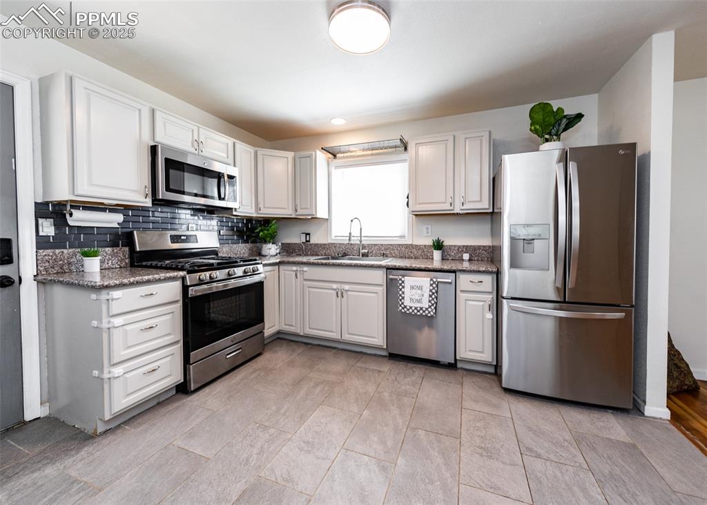 Image 10 of 25: Kitchen with appliances with stainless steel finishes, a sink, tasteful bac