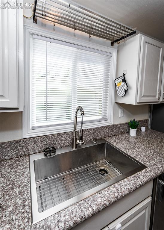 Image 12 of 25: Kitchen view of a sink, dark countertops, and white cabinetry