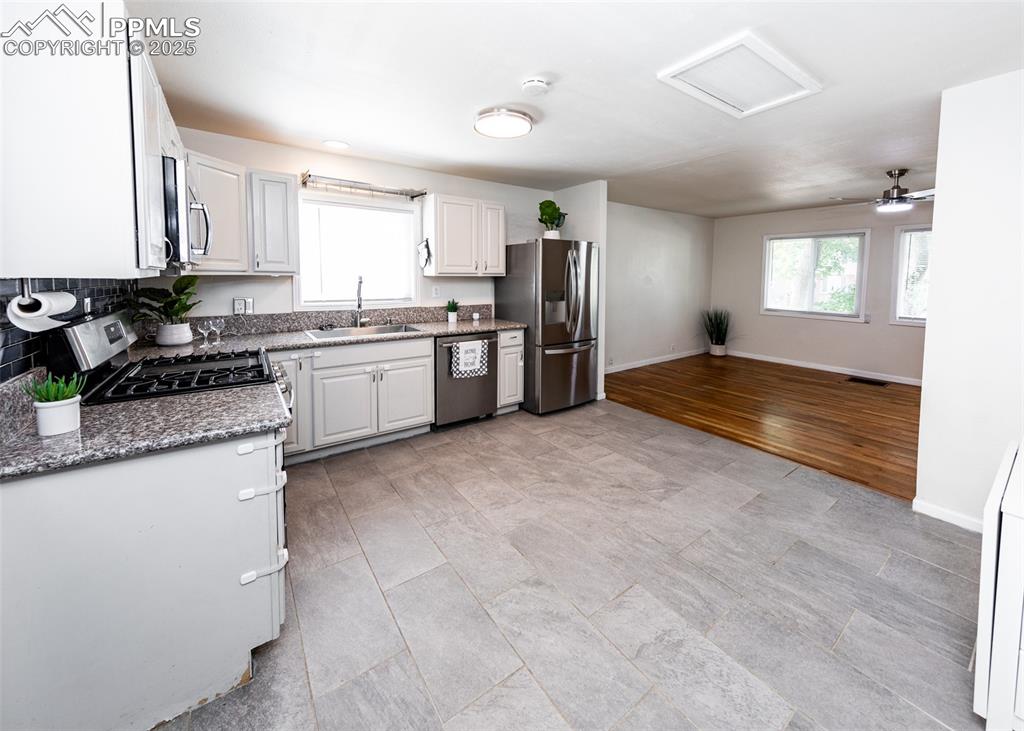 Image 13 of 25: Kitchen with stainless steel appliances, a sink, baseboards, stone countert