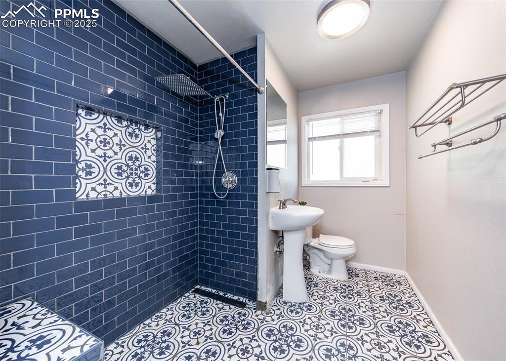 Image 15 of 25: Full bath featuring a tile shower, baseboards, and toilet