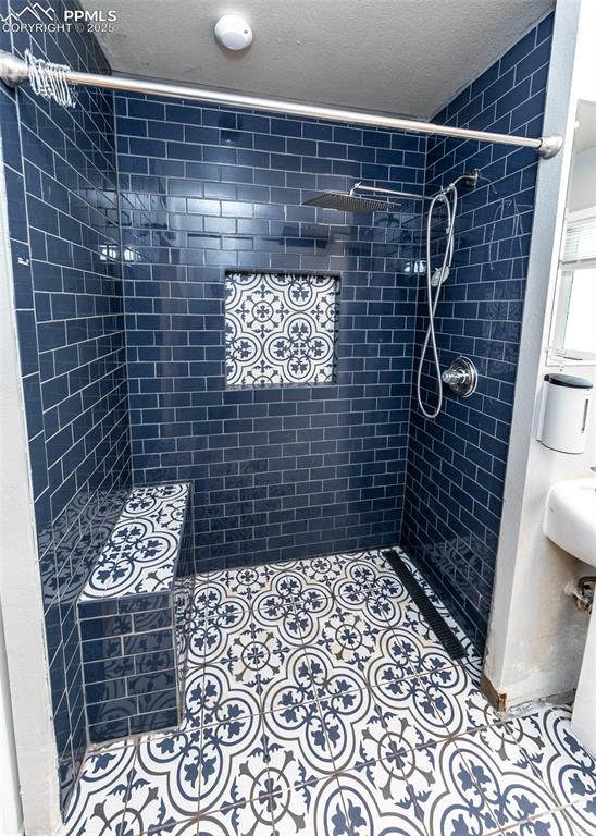 Image 16 of 25: Full bathroom featuring a tile shower and a textured ceiling