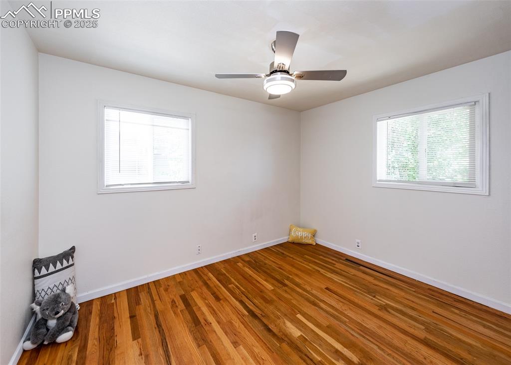 Image 19 of 25: Unfurnished room with wood finished floors, baseboards, and a ceiling fan
