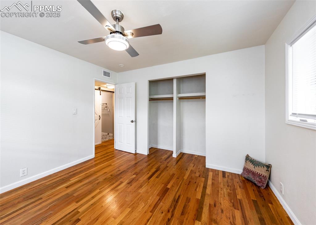 Image 20 of 25: Unfurnished bedroom with a closet, wood finished floors, baseboards, and a 