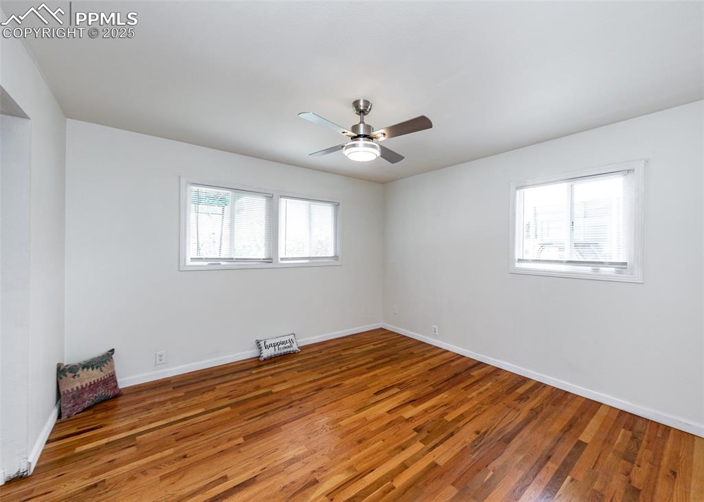 Image 22 of 25: Spare room featuring wood finished floors, a ceiling fan, and baseboards