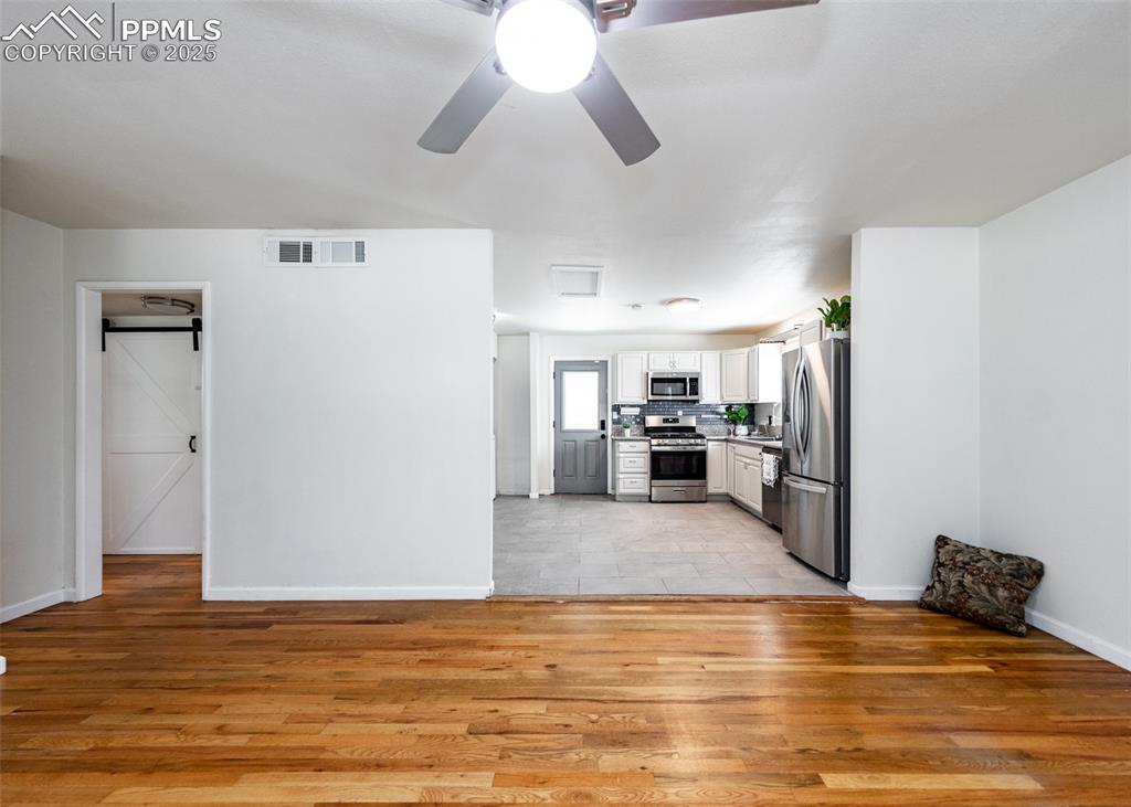 Image 8 of 25: Kitchen featuring appliances with stainless steel finishes, light wood-styl