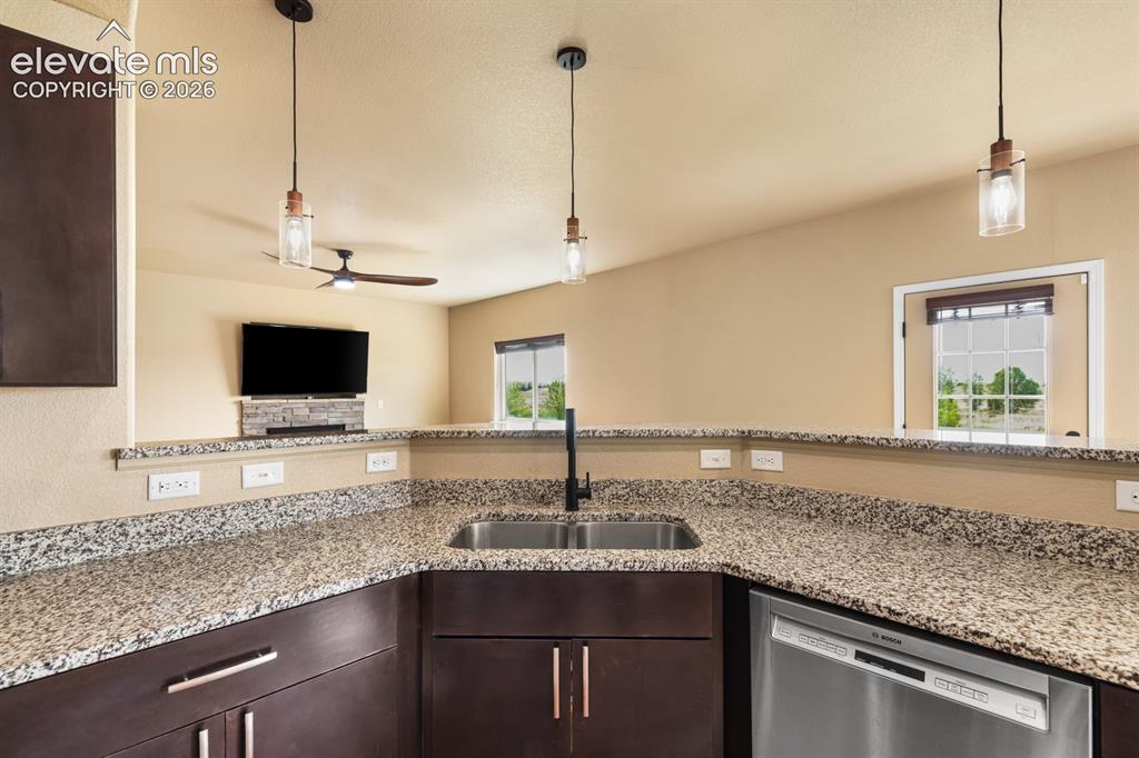 Image 15 of 50: Kitchen featuring dark wood cabinetry with brushed nickel hardware, granite