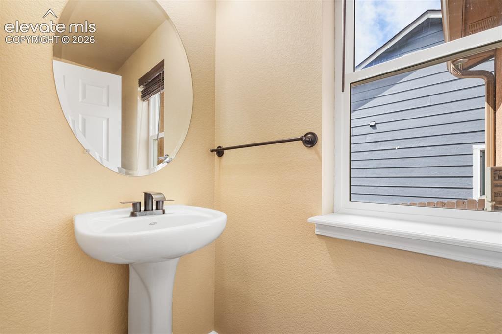 Image 17 of 50: Pedestal sink with chrome faucet, circular frameless mirror, and bronze tow