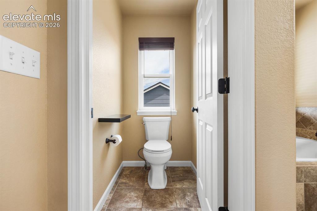 Image 20 of 50: Private water closet with a window, dark wood-finish blinds, and a built-in