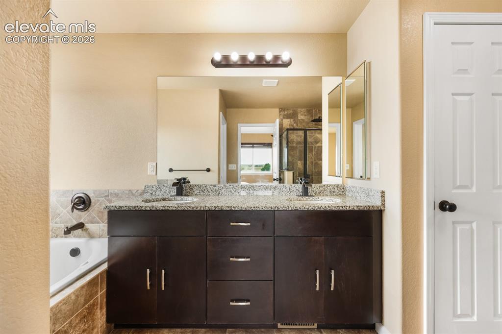 Image 25 of 50: Double vanity with stone countertop, undermount sinks, and dark wood-finish