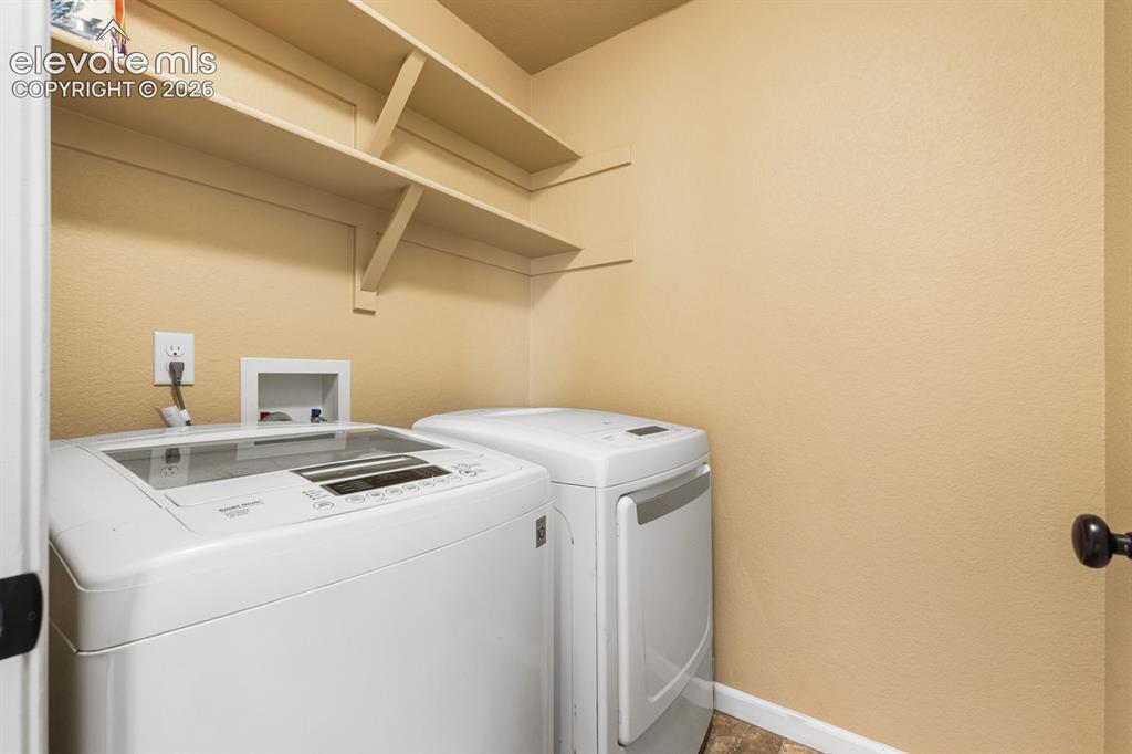 Image 29 of 50: Dedicated laundry area featuring wall-mounted shelving and durable flooring