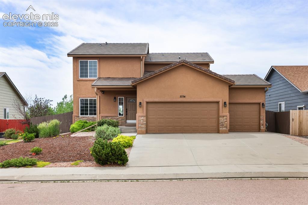 Image 3 of 50: Stucco exterior featuring a dual-pitch roof, stone accents, and a three-car