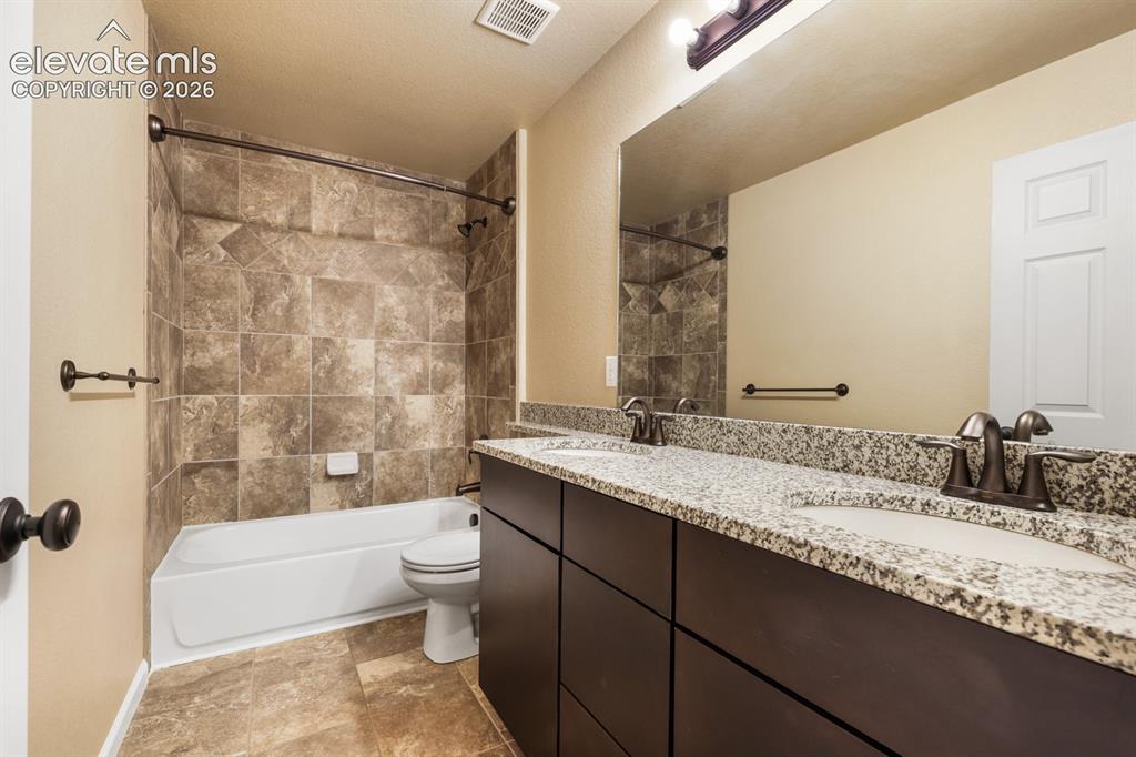 Image 30 of 50: Bathroom featuring a double vanity with granite countertop, integrated sink
