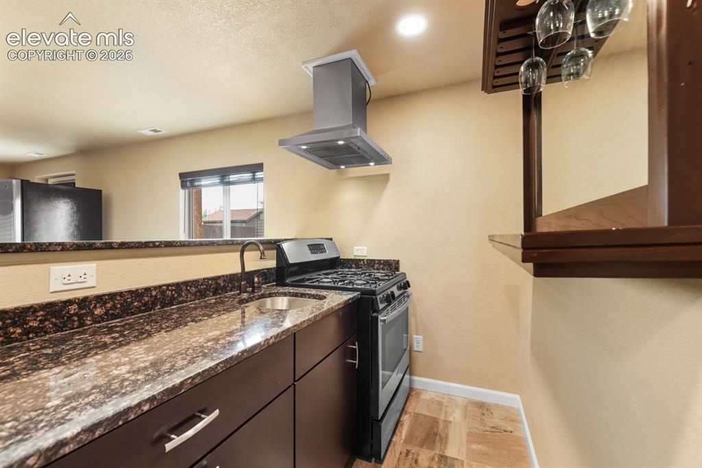 Image 39 of 50: Kitchenette featuring granite-look countertops, dark wood-finish cabinetry,