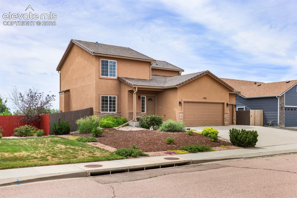 Image 4 of 50: Stucco exterior with stone accents and an attached garage