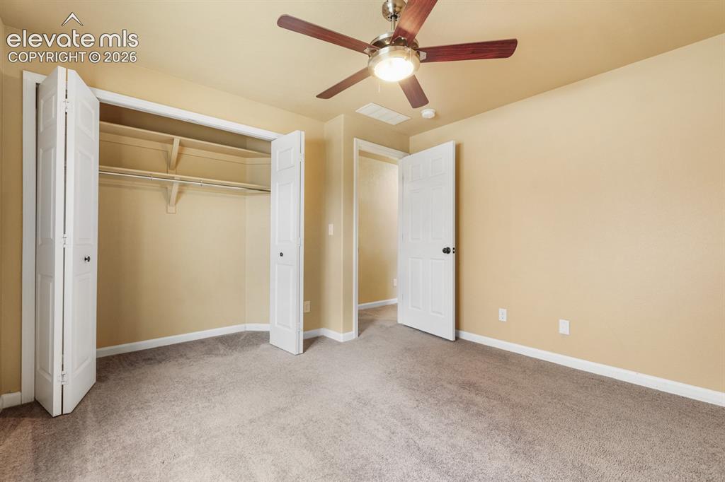 Image 41 of 50: Carpeted room featuring a ceiling fan with light fixture, neutral-toned wal