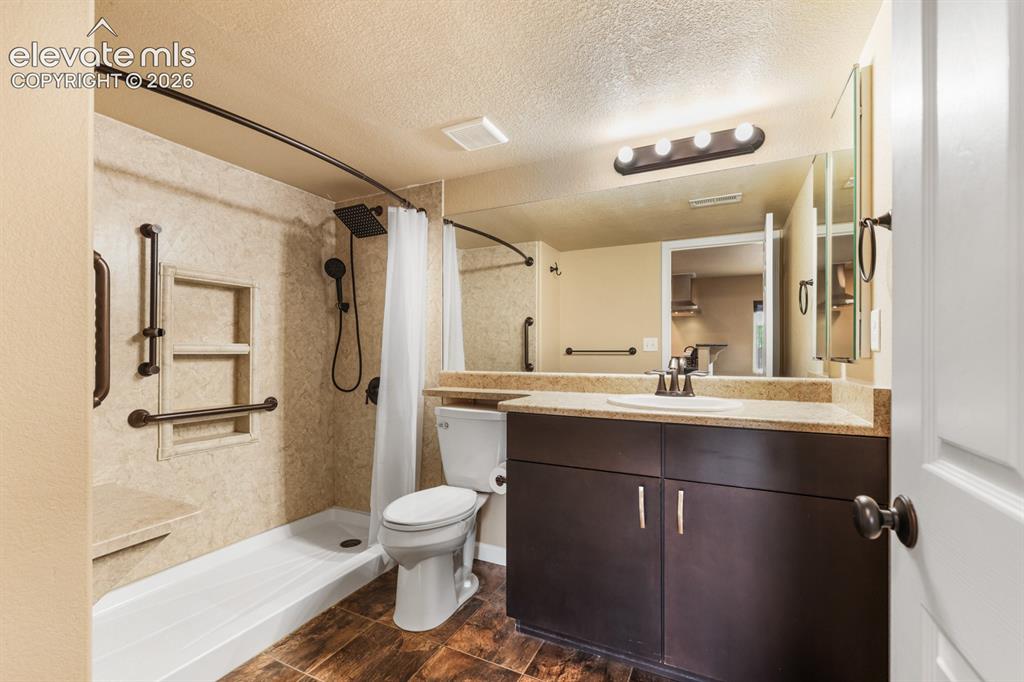 Image 43 of 50: Bathroom featuring a walk-in shower with built-in shelving and a bench, dar