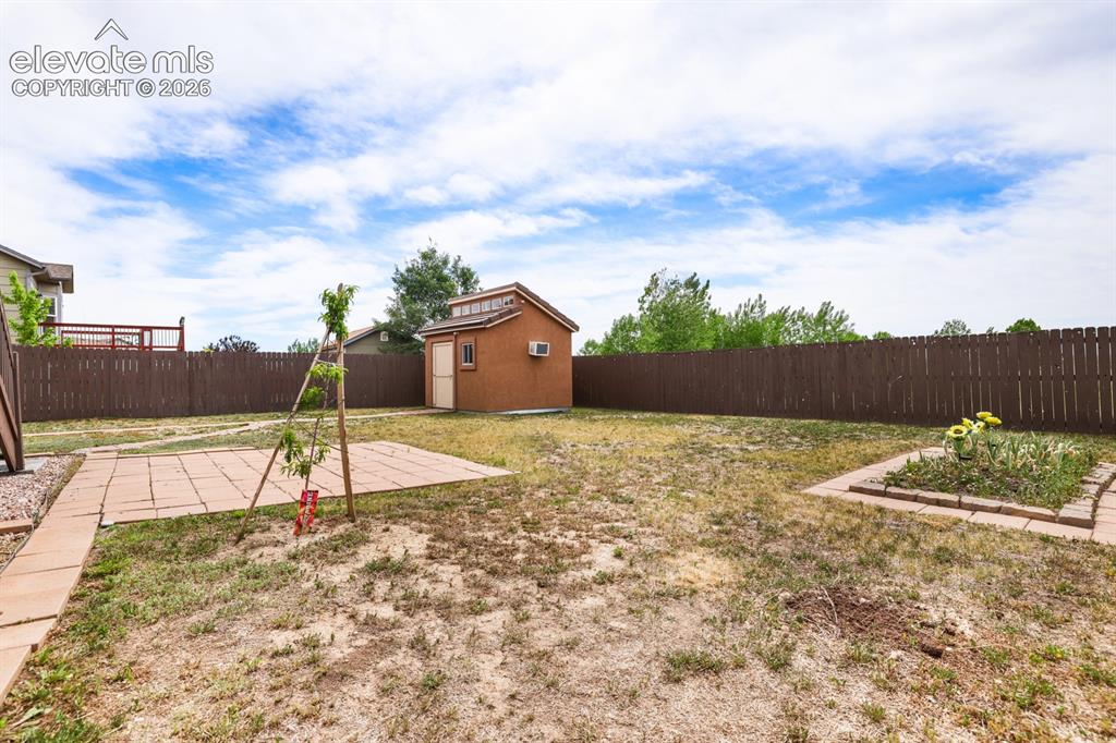 Image 45 of 50: Expansive fenced backyard featuring a detached storage shed with a window,