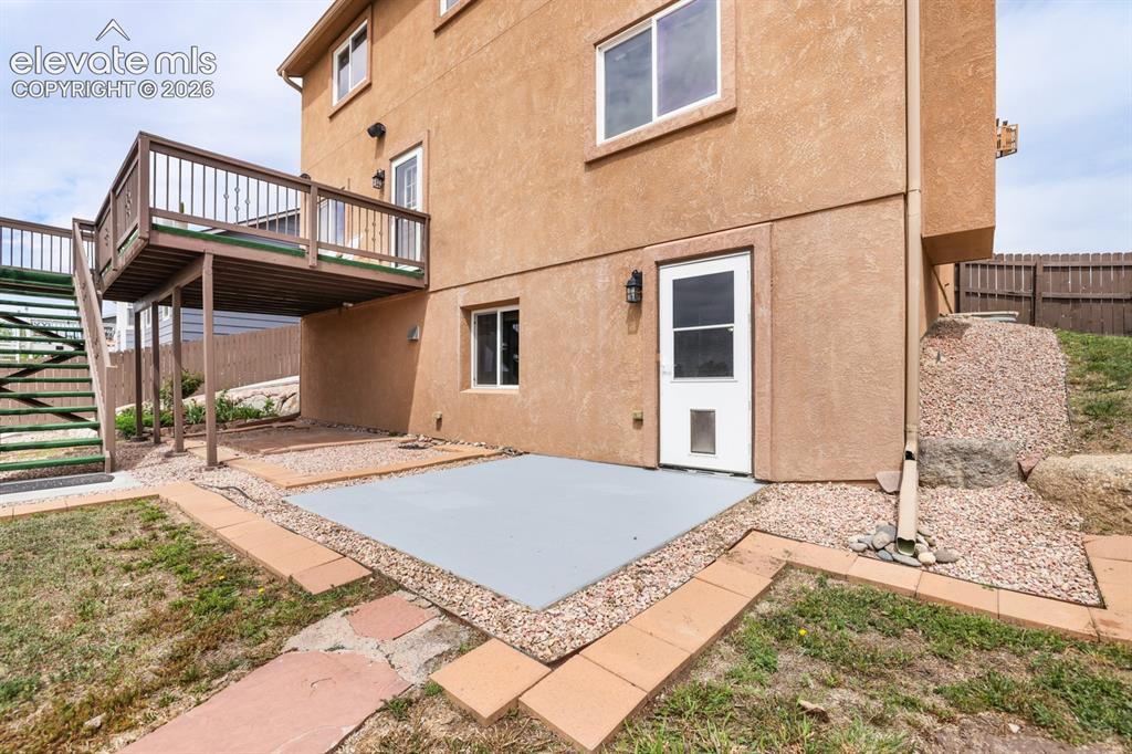 Image 49 of 50: Lower-level patio area featuring a concrete pad, gravel landscaping, and a