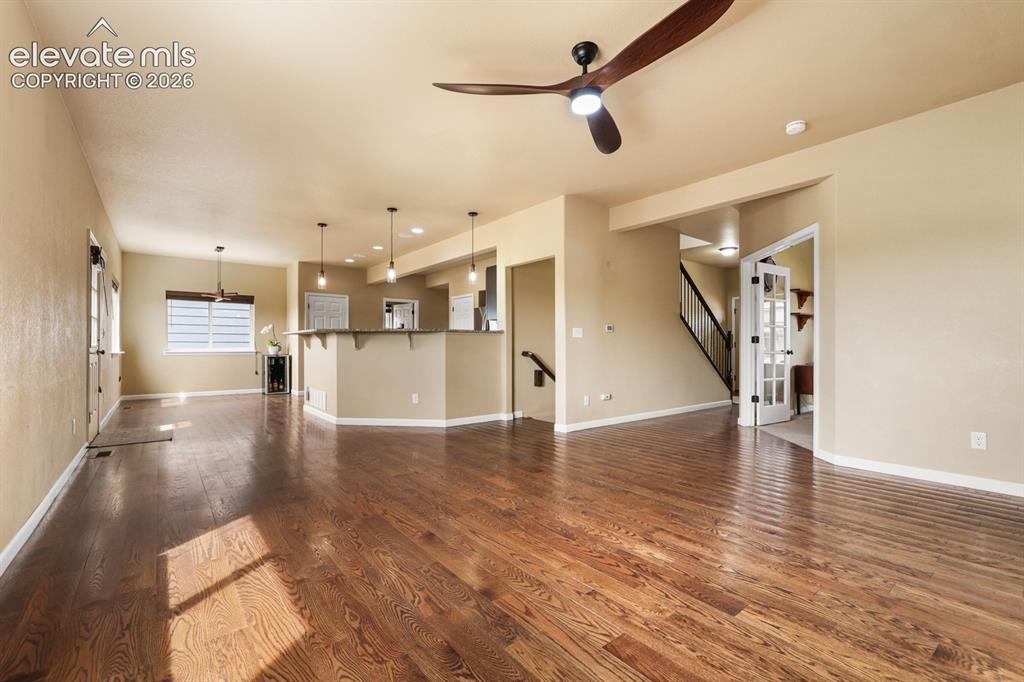 Image 7 of 50: Spacious main living area featuring wood-finish flooring, a contemporary ce