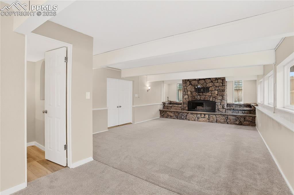 Image 19 of 37: Lower level living area with stone fireplace and walk out to covered patio.