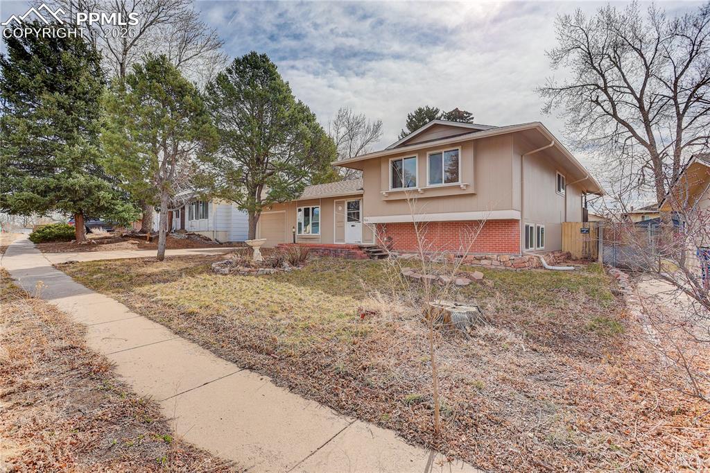 Image 2 of 37: Corner view of the home showing the front yard and mature trees.