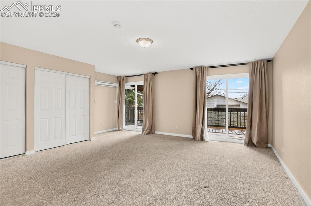 Image 22 of 37: Spacious primary bedroom with large sliding glass doors, deck access, and g