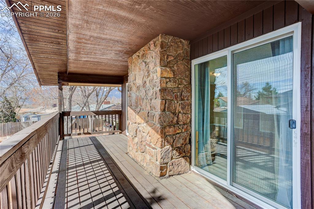Image 26 of 37: Covered deck off the primary bedroom overlooking the backyard.