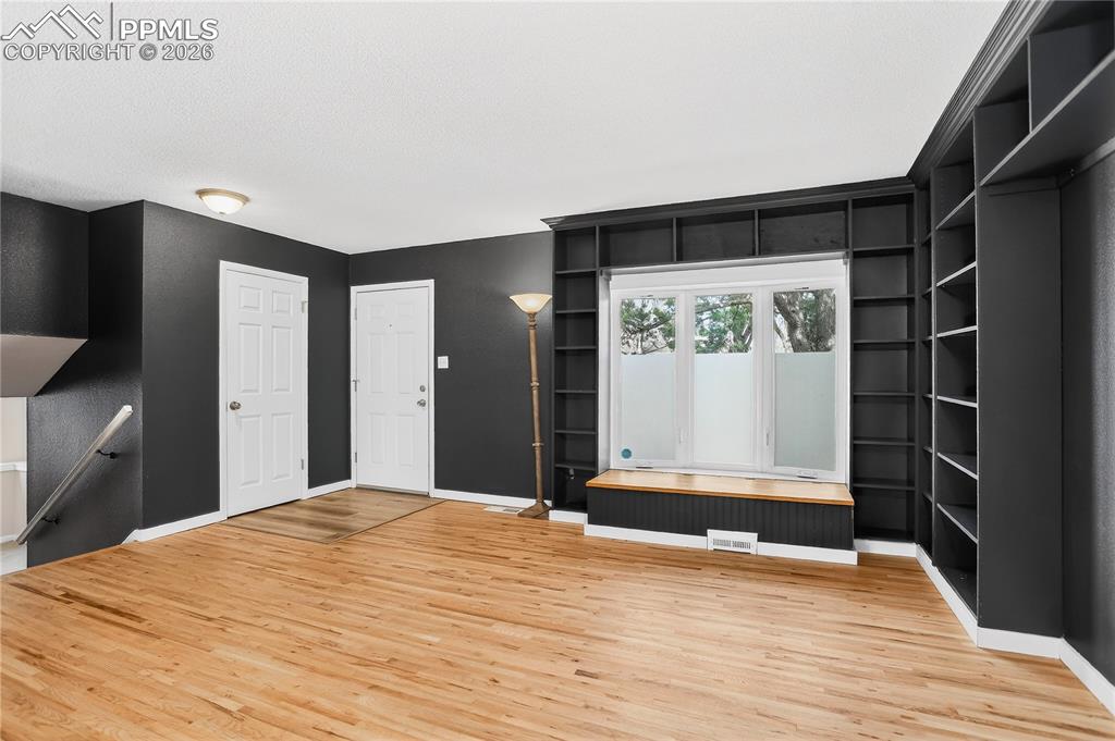 Image 6 of 37: Living room with hardwood flooring, built-in shelving, and bay window with 