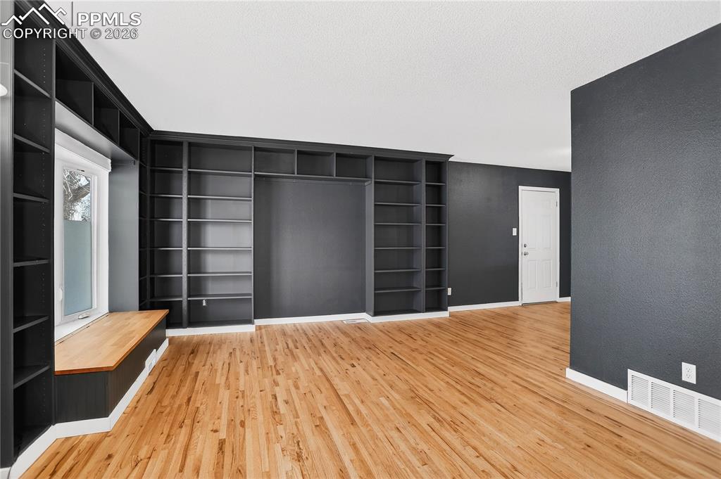 Image 8 of 37: Living room with hardwood flooring, built-in shelving, and bay window with 