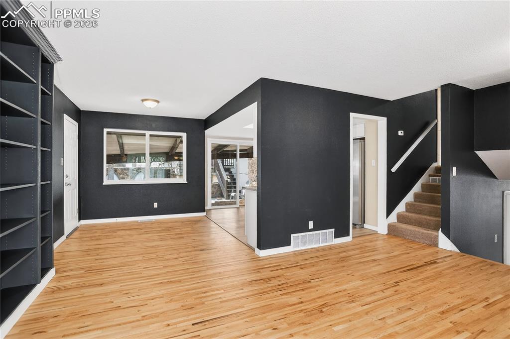 Image 9 of 37: Unfurnished living room with stairway and light wood finished floors