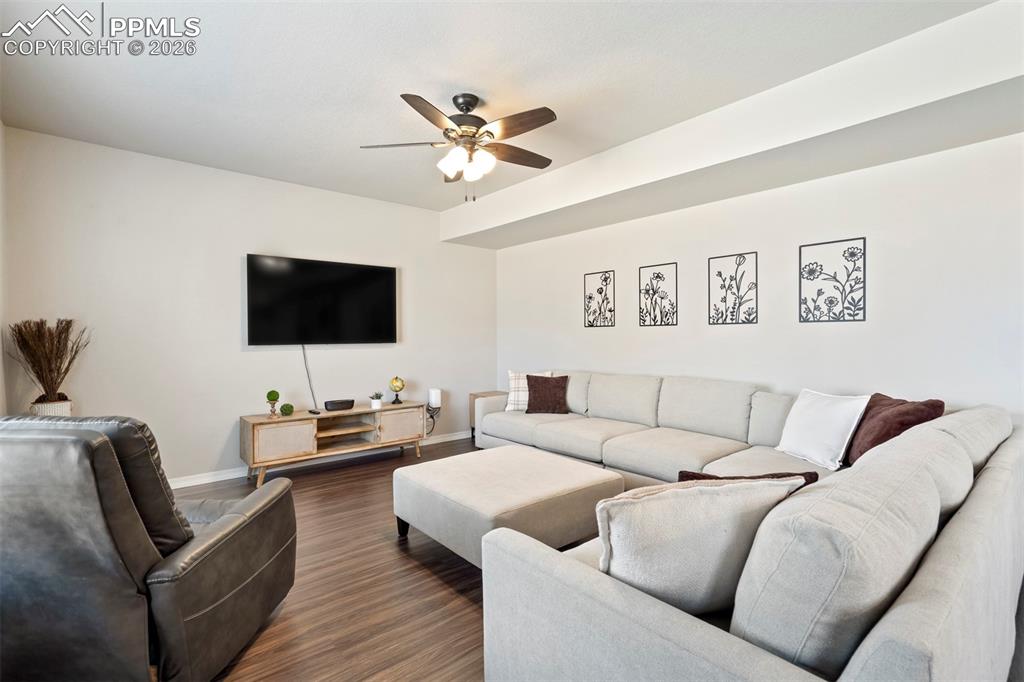 Image 14 of 46: Spacious living area featuring wood-finish flooring, a ceiling fan with int