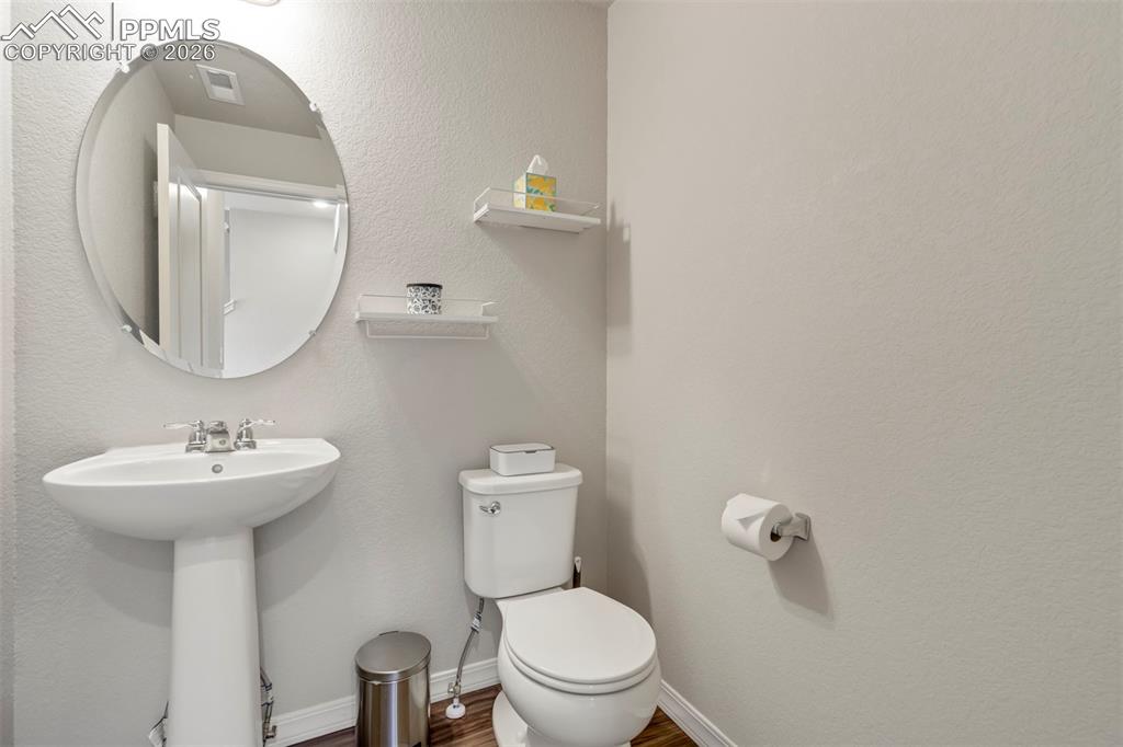 Image 19 of 46: Pedestal sink with chrome fixtures, oval mirror, and wall-mounted shelving