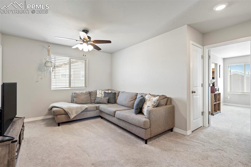 Image 22 of 46: Carpeted common area featuring a ceiling fan with integrated lighting, a wi