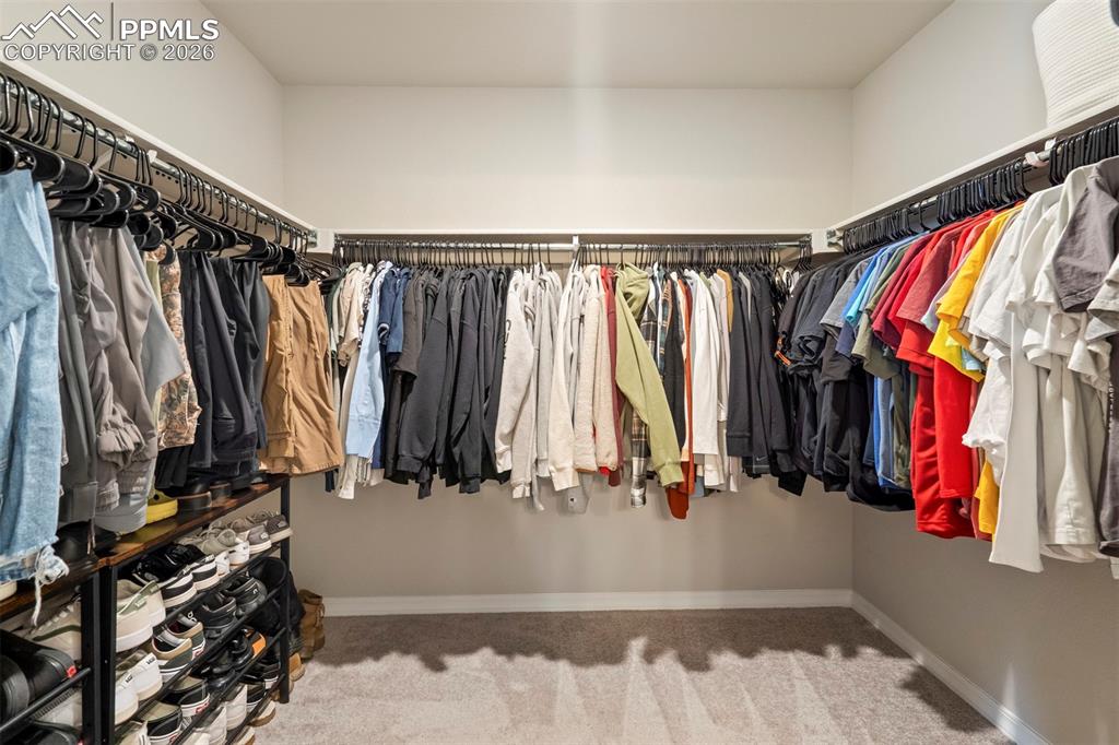 Image 30 of 46: Spacious walk-in closet featuring extensive hanging storage, light gray wal