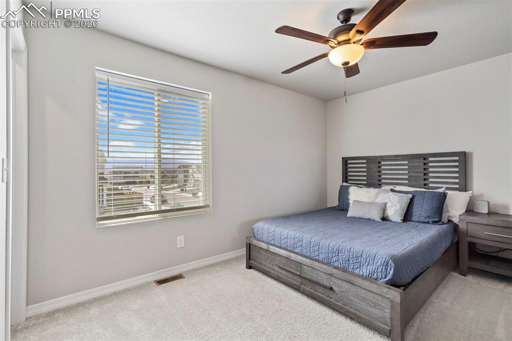 Image 31 of 46: Light-filled room featuring a broad window with horizontal blinds, carpeted