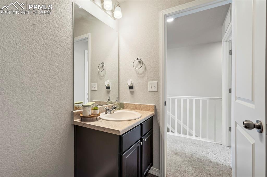 Image 34 of 46: Bathroom vanity with dark wood-finish cabinetry, a single basin sink, and a