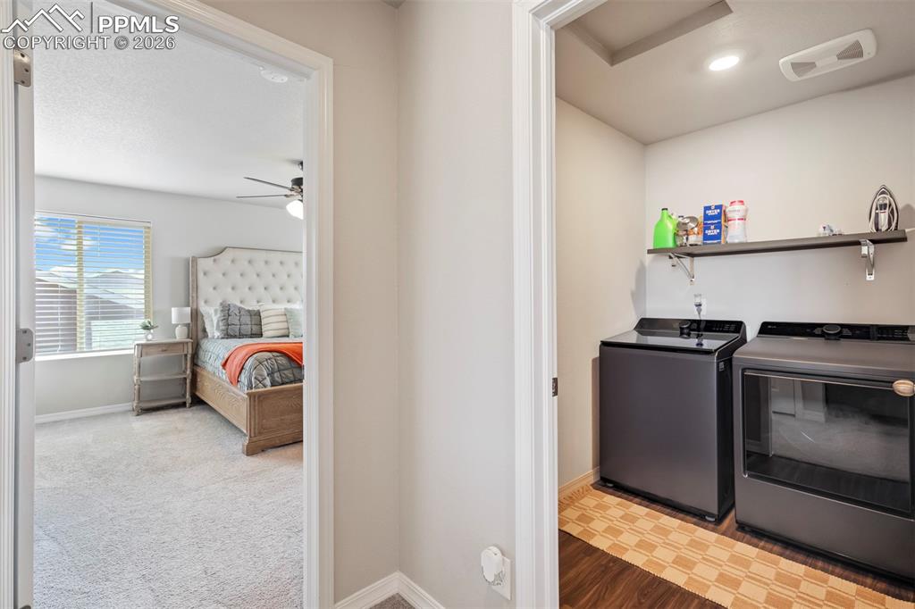 Image 37 of 46: Dedicated laundry area with durable dark wood-finish flooring and an overhe