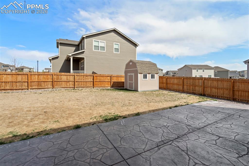 Image 39 of 46: Expansive backyard featuring stamped concrete patio, wood privacy fencing, 