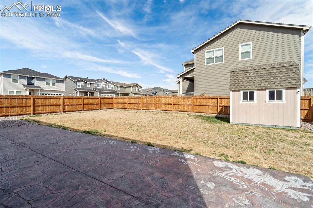 Image 42 of 46: Spacious backyard featuring a stamped concrete patio, a full wood privacy f
