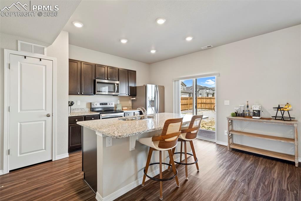 Image 5 of 46: Kitchen featuring dark wood cabinetry, stainless steel appliances, a center
