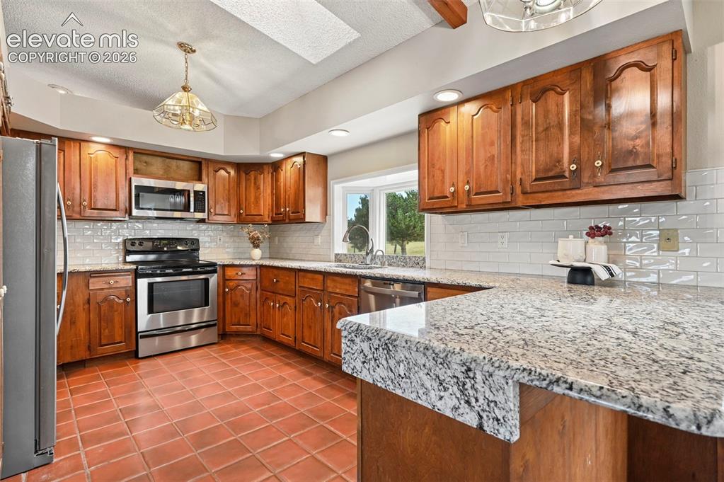 Image 19 of 50: Kitchen featuring Granite Counters, Stainless Appliances, Wood Cabinets.