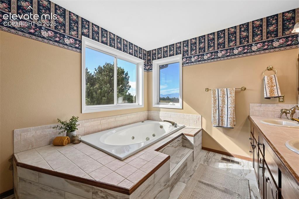 Image 25 of 50: Built-in jetted tub with tiled surround and double vanity.