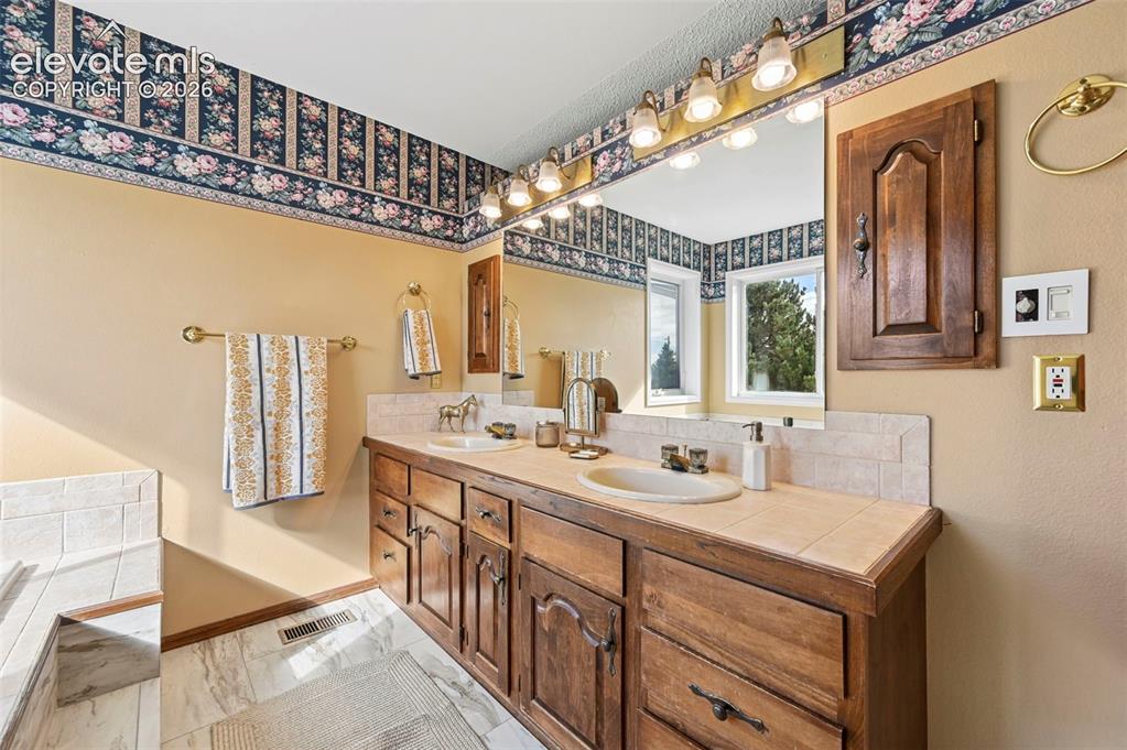 Image 26 of 50: Dual vanity and a tile countertop