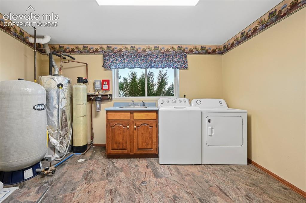 Image 29 of 50: Laundry area with hot water heater, utility sink, and water softener