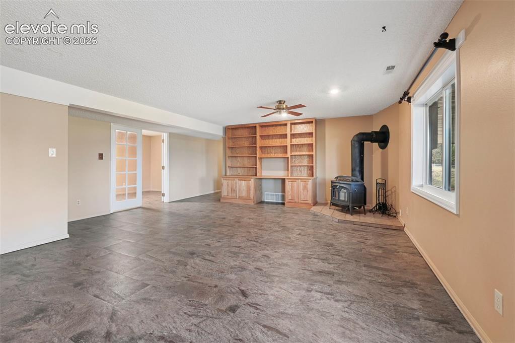 Image 30 of 50: Downstairs living area with built-in wood bookcase, and a wood-burning stov