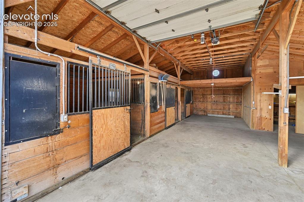 Image 42 of 50: Barn interior featuring 2 garage doors, heated tack room.