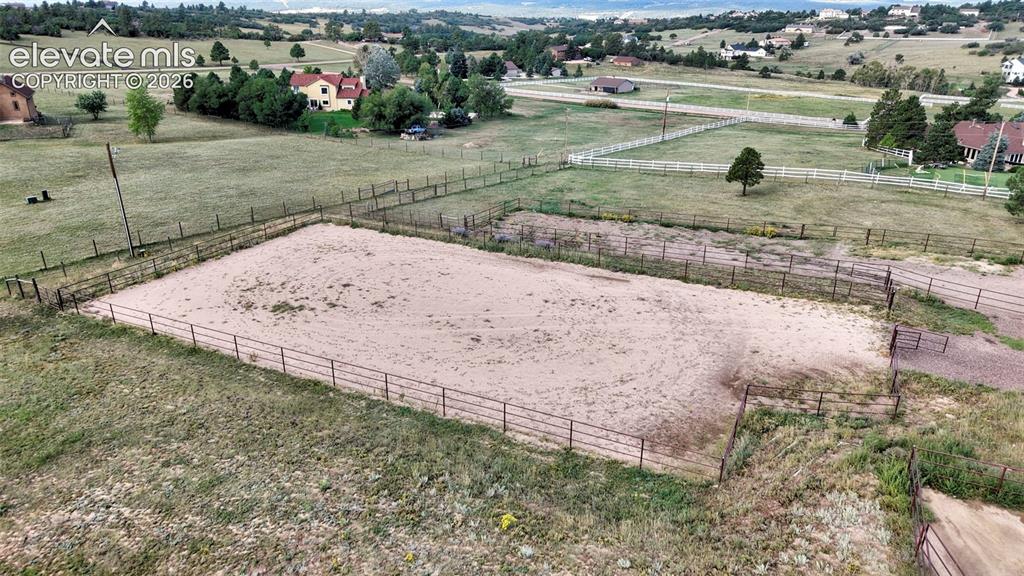 Image 46 of 50: Fenced equestrian arena with granite footing, surrounded by expansive grass