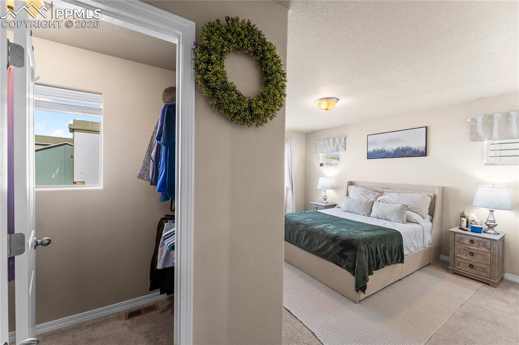 Image 19 of 37: The primary bedroom offers a calm, neutral retreat with soft natural light